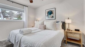 Een keurig opgemaakt slaapkamer met een bed, nachtkastje en een plafondventilator.