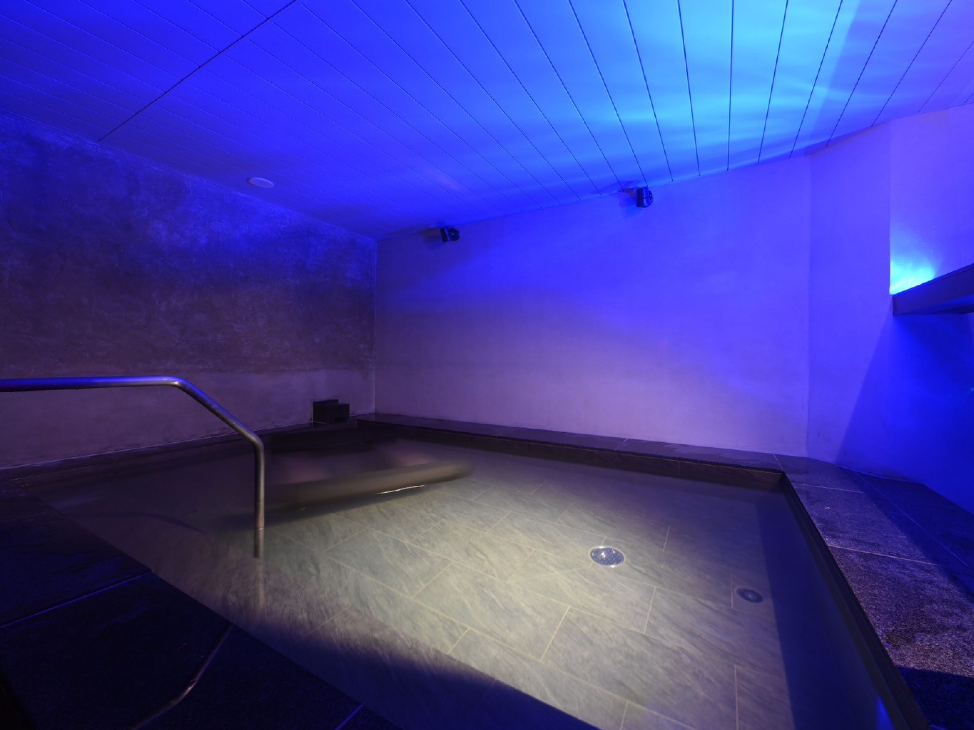 A room with a large, empty bathtub, a small window, and a metal railing.