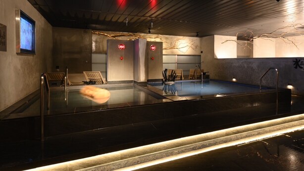 A modern indoor pool with a glass barrier, wooden deck, and a ceiling with red lights. - The Centurion Sauna Rest & Stay Sapporo Male Only (Sapporo)