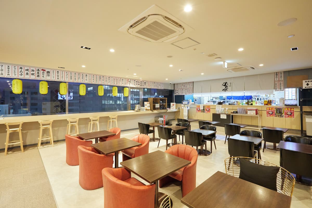 A restaurant with a counter, tables, and chairs.