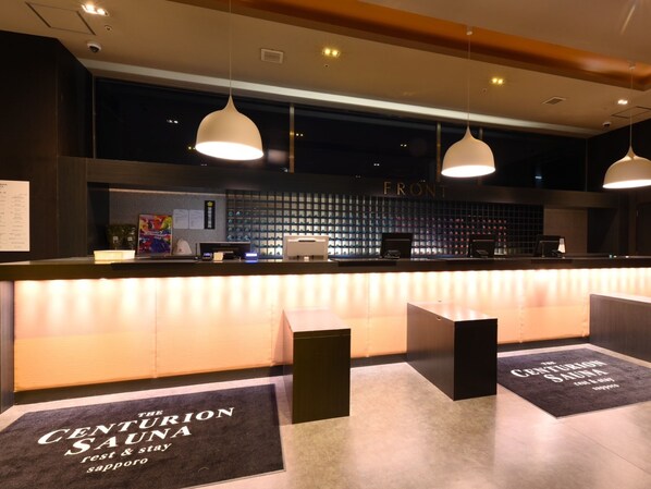 A reception area with a counter, pendant lighting, and a wall displaying a 'FRONT' sign. - The Centurion Sauna Rest & Stay Sapporo Male Only (Sapporo)