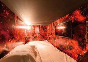 A bedroom with a bed, a wall-mounted TV, and a galaxy-themed wall design. - The Centurion Sauna Rest & Stay Sapporo Male Only (Sapporo)