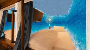 A room with a bed, curtains, and a view of the ocean. - The Centurion Sauna Rest & Stay Sapporo Male Only (Sapporo)