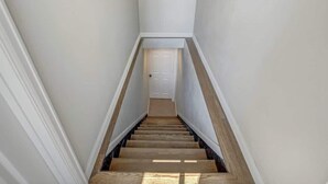 Un escalier étroit avec des marches en bois et des murs blancs.