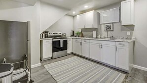 Une cuisine moderne avec des meubles blancs, un four encastré et un tapis à rayures.