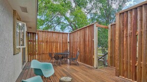 Eine Holzterrasse mit Tisch und Stühlen, ein Holzzaun und ein Baum im Hintergrund.