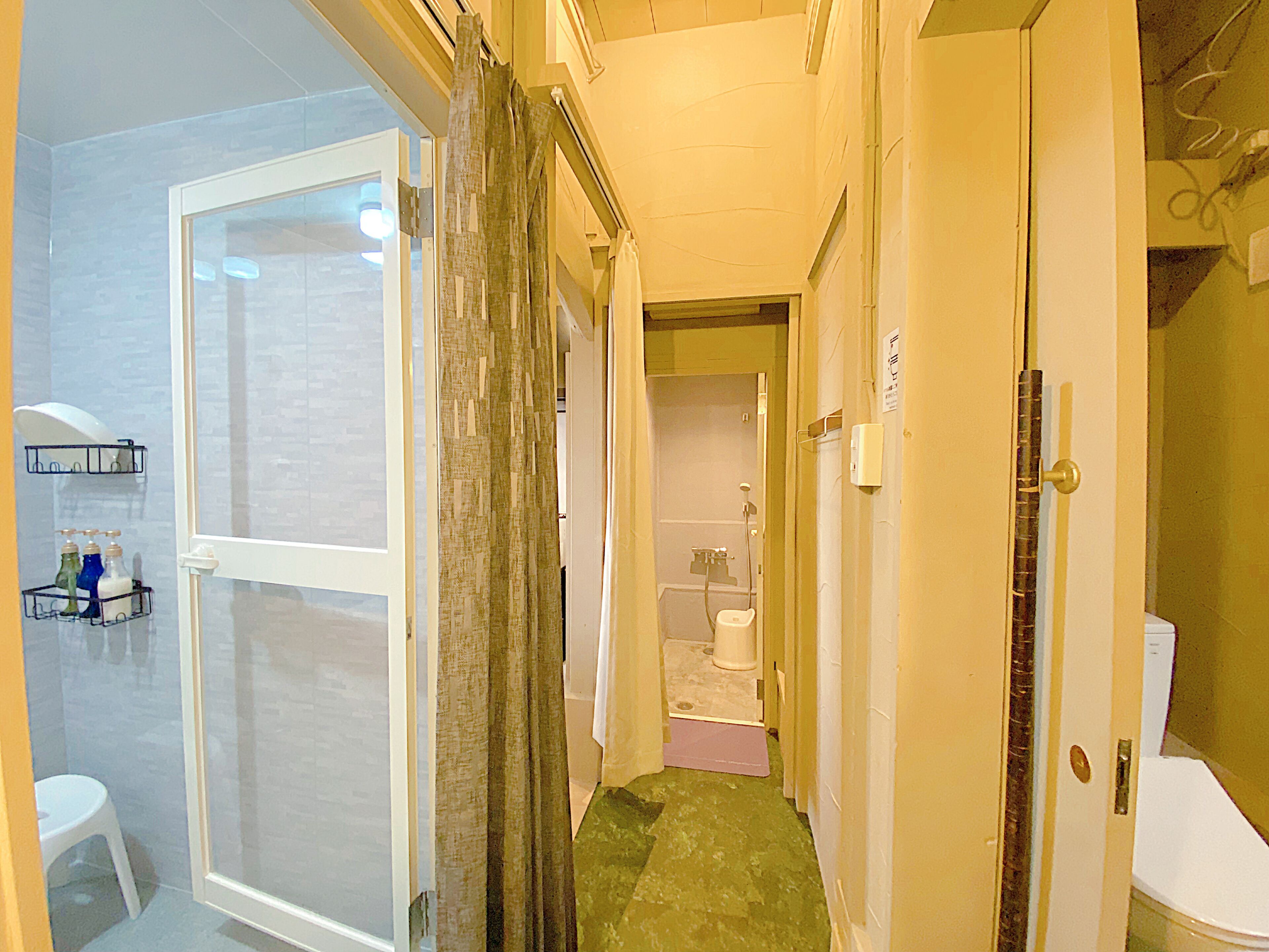 A narrow hallway with a glass door leading to a bathroom, a shower area, and a toilet visible in the background.