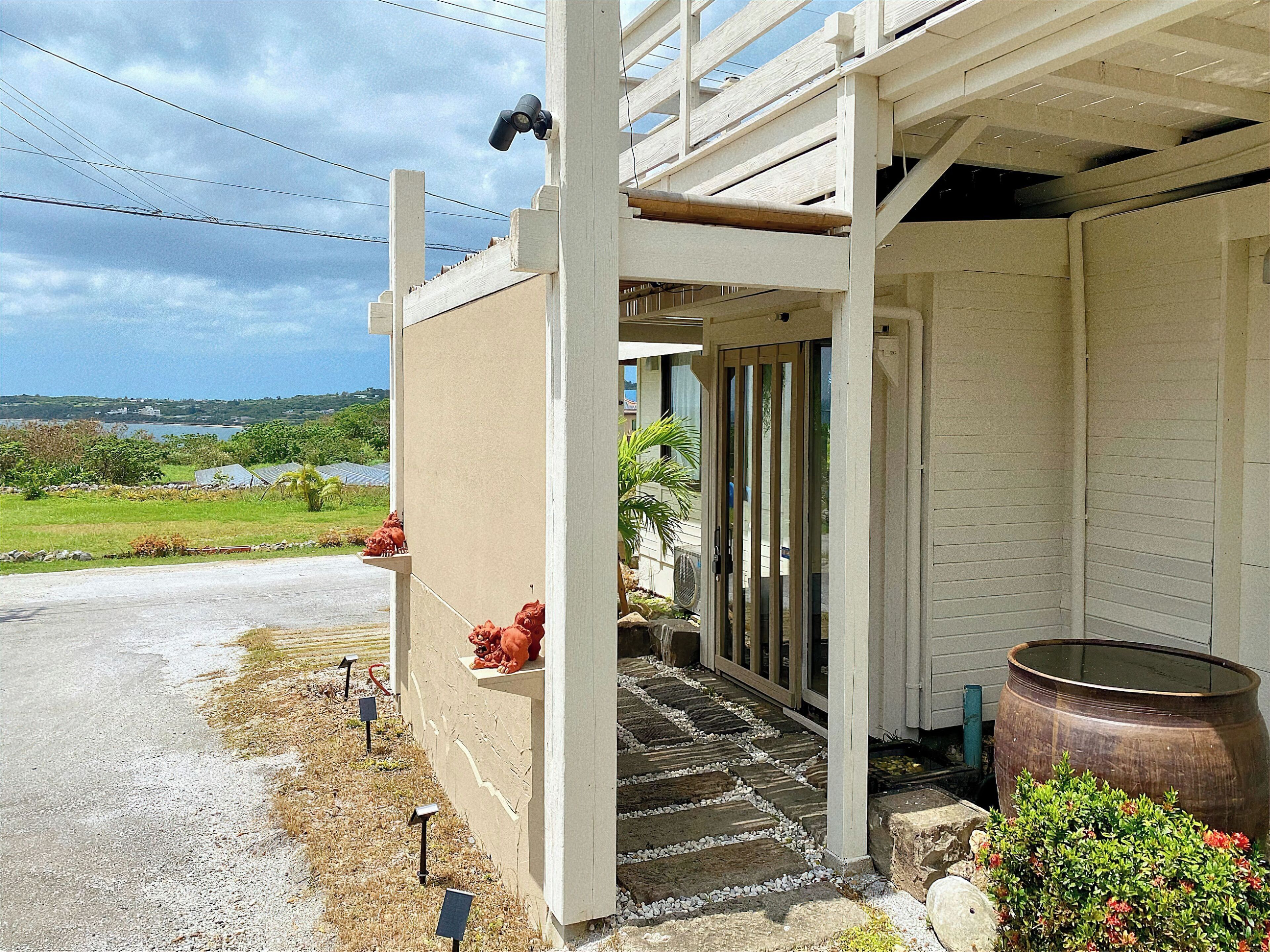 A building with a covered porch, a large water tank, and a view of a green landscape.