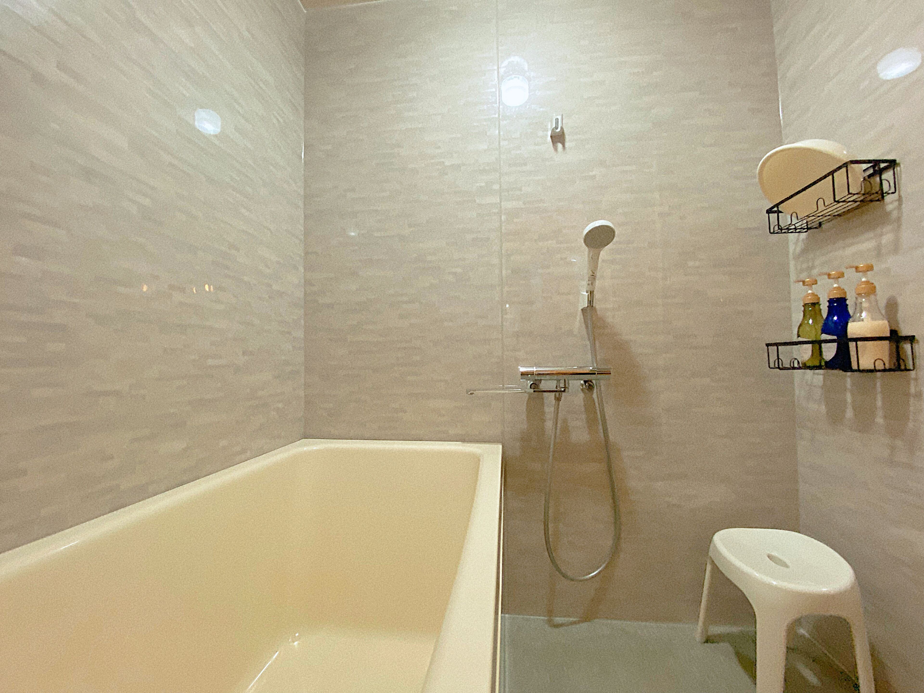 Une salle de bain avec une baignoire, une douche et des toilettes. On trouve des articles de toilette sur une étagère.