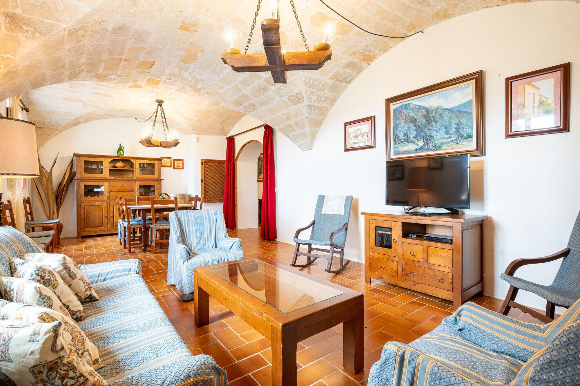A cozy living room with a stone ceiling, wooden furniture, a television, and artwork on the walls.