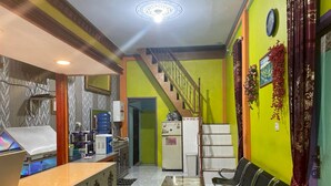 A reception area with a counter, chairs, a staircase, and a refrigerator. - Hotel O Lima Saudara Syariah (Padang)