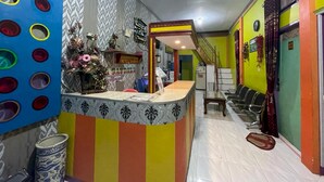 A reception area with a colorful counter, a staircase, and a seating area. - Hotel O Lima Saudara Syariah (Padang)