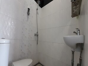 A small bathroom with a toilet, a shower, and a sink.