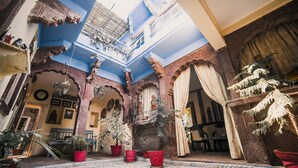 Une cour intérieure aux couleurs bleu et jaune, agrémentée de plantes en pot et présentant un style architectural traditionnel.