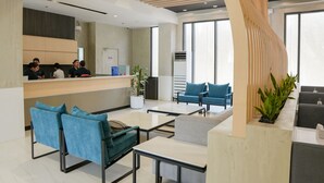 A modern reception area with a counter, seating, and large windows. - Copenhagen Residences (Ormoc)