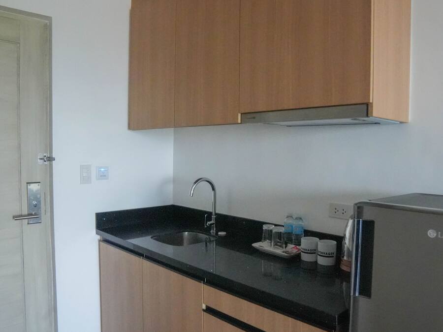 Una cocina con armarios de madera, un lavamanos de acero inoxidable y un refrigerador LG.