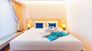 A hotel room with a large bed, two pillows, a headboard, bedside lamps, and a window with curtains. - Copenhagen Residences (Ormoc)