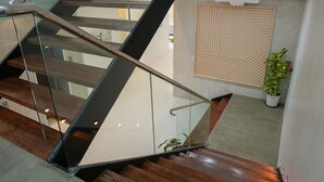 A modern staircase with glass railings and wooden steps. - Copenhagen Residences (Ormoc)