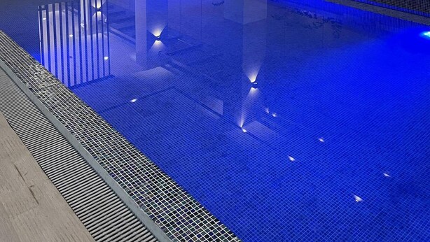 A modern indoor swimming pool with clear water, surrounded by minimalist architecture and ambient lighting. - Copenhagen Residences (Ormoc)