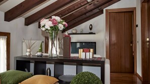 A cozy living room with a dark wooden console table, a vase with flowers, a gnome figurine, and a bookshelf. - Entire Accommodation in Castelfranco Veneto (Castelfranco Veneto)