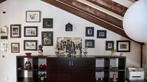 A room with a dark wooden cabinet, shelves with decorative items, and a wall adorned with framed pictures. - Entire Accommodation in Castelfranco Veneto (Castelfranco Veneto)