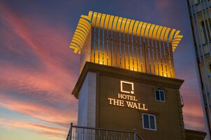 Un hotel llamado "Hotel The Wall" con un diseño arquitectónico distintivo que presenta un techo inclinado y una estructura vertical prominente.