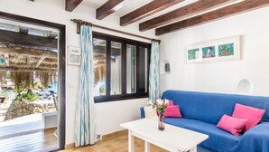 Une pièce avec un canapé bleu, une table blanche et une vue sur une piscine et un espace extérieur.