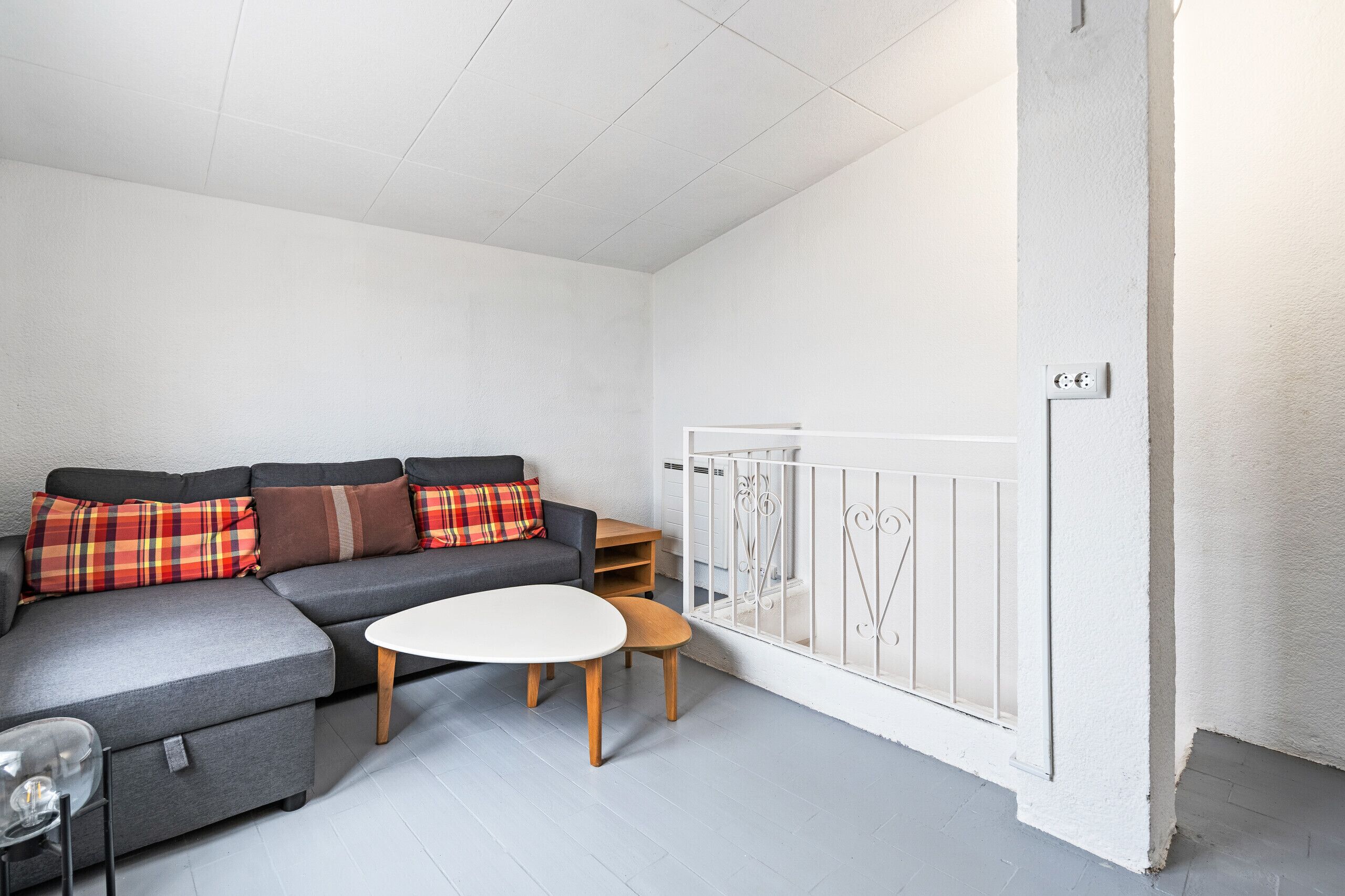 Ein modernes Wohnzimmer mit einer grauen Eckcouch, einem weißen Couchtisch und einem kleinen Holznachttisch.
