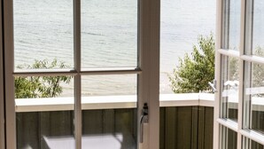 A view through a glass door to a balcony overlooking the sea, with a wooden deck and a view of the ocean. - Oakvale Villa Sand (Aahus)