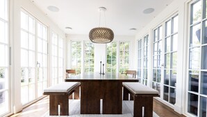 A spacious room with a large wooden dining table, benches, and a unique chandelier. - Oakvale Villa Sand (Aahus)
