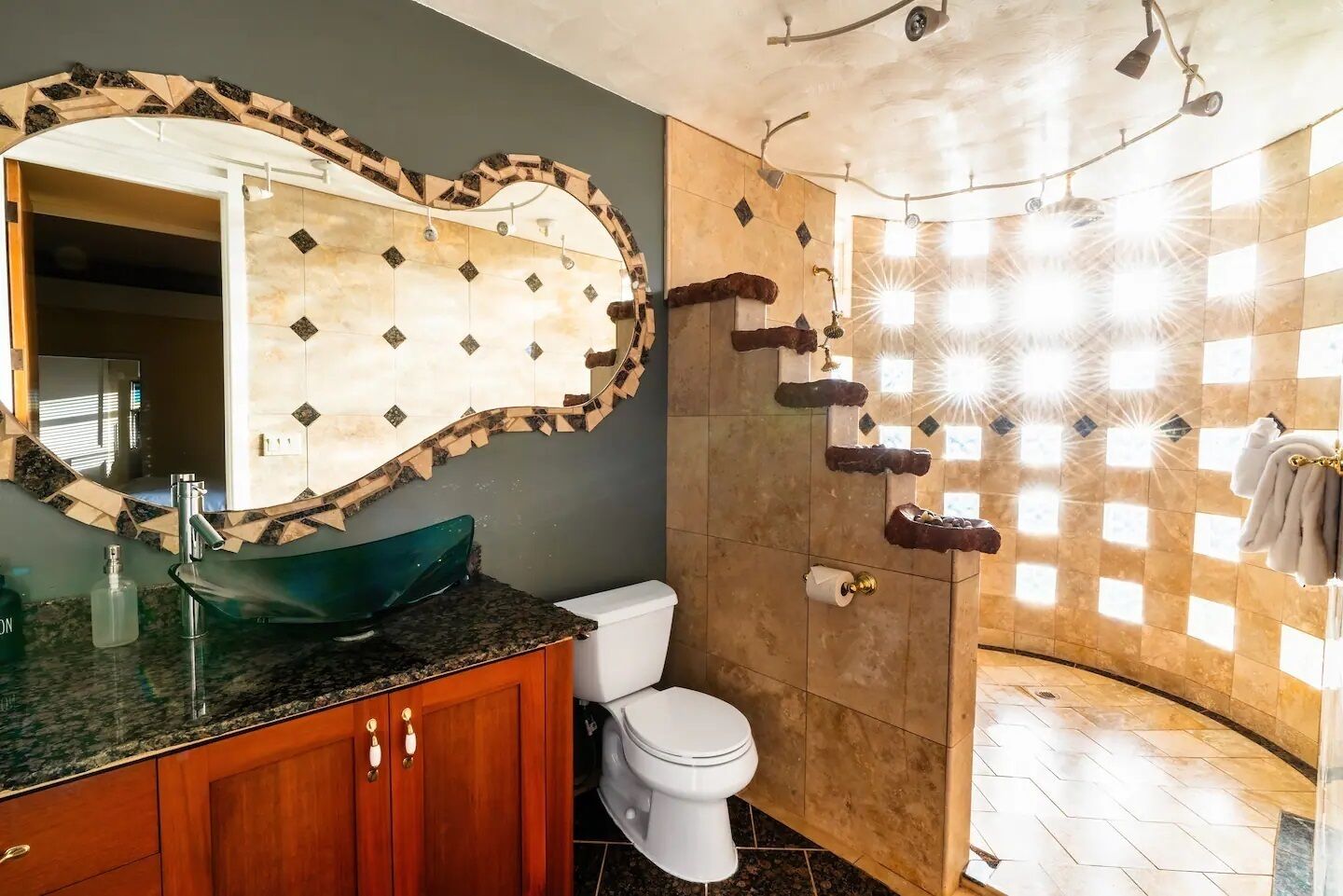 Une salle de bain avec un grand miroir, un lavabo, des toilettes et un espace douche.