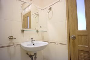 Un baño con un lavamanos blanco, un espejo y una puerta de madera.