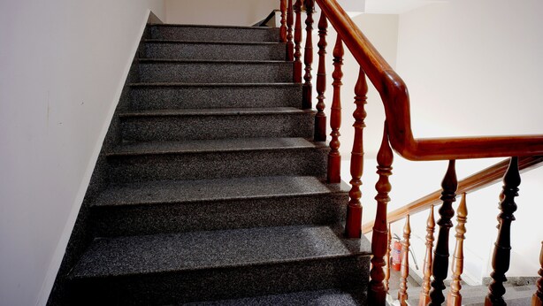 A staircase with wooden balusters and a handrail, leading to an upper floor.