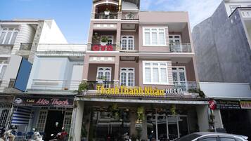A hotel with a sign reading "Thanh Thanh Nhân Hotel" and a cafe named "Móc Thach" below it.