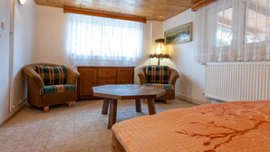 Een gezellige kamer met een bed, twee fauteuils, een tafeltje en een radiator.