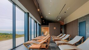 A modern spa area with sun loungers and a large window overlooking a scenic view.