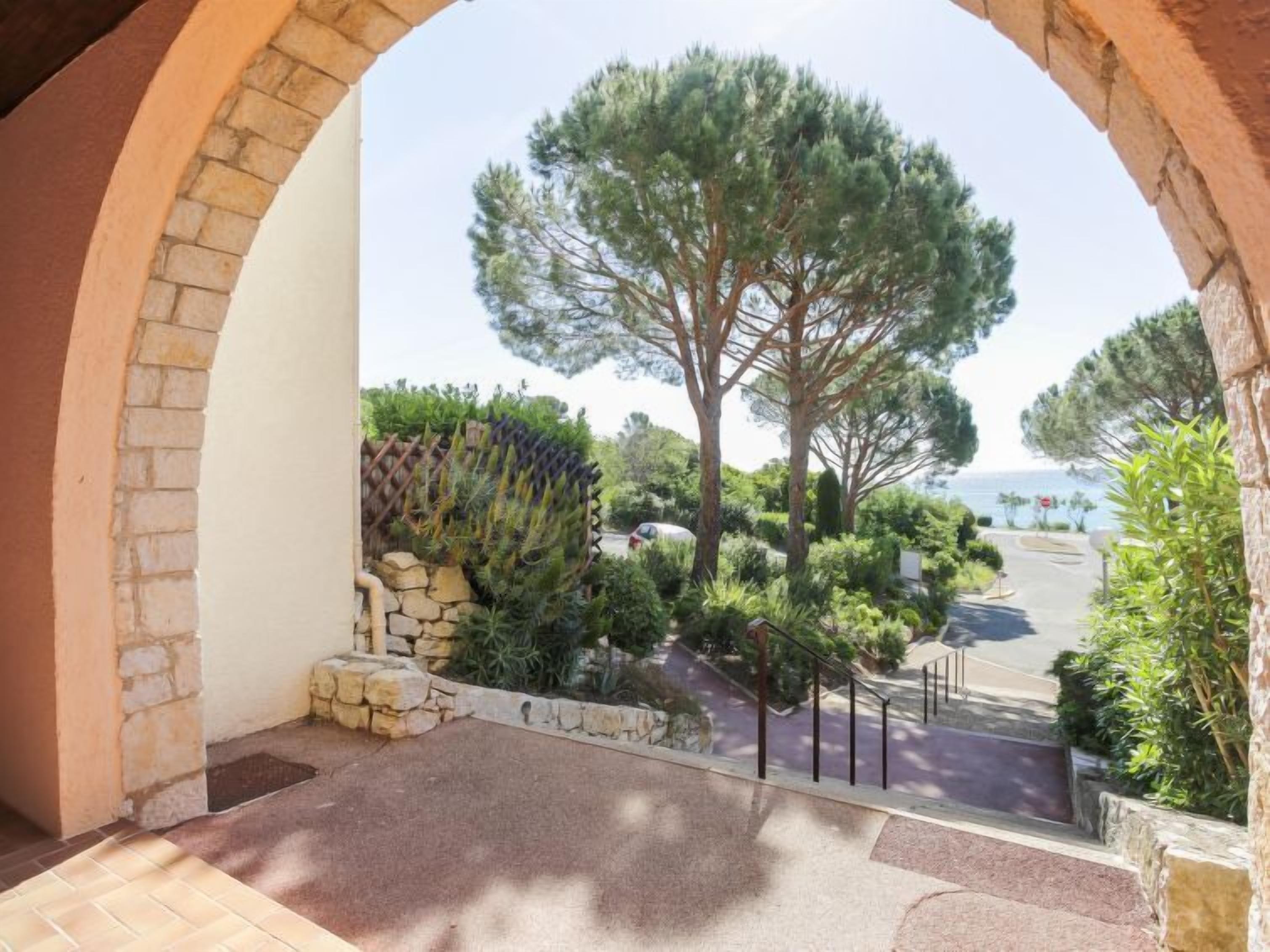 Un balcon avec un mur en pierre, une vue sur un pin et une zone pavée agrémentée d’une rambarde.