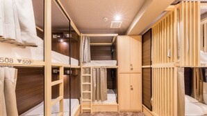 Una habitación de hotel compacta con literas, un armario y un pequeño guardarropa.