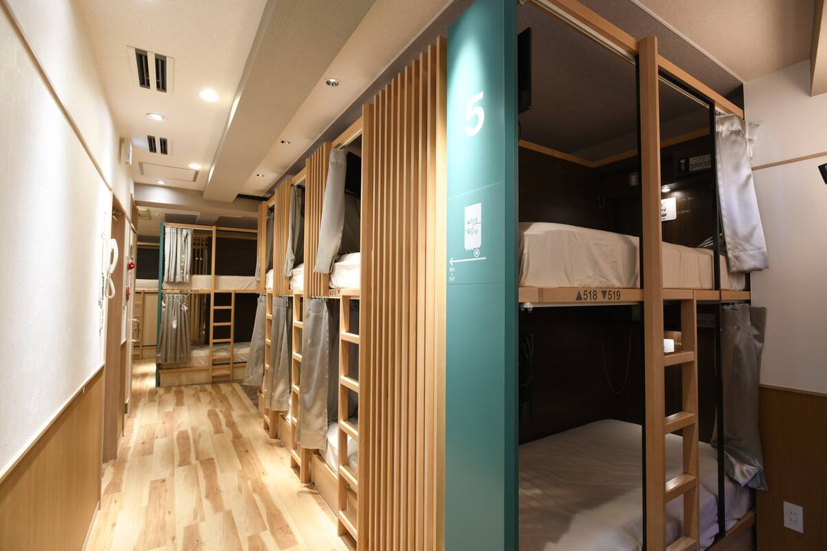A corridor with bunk beds, wooden partitions, and a number '5' sign.
