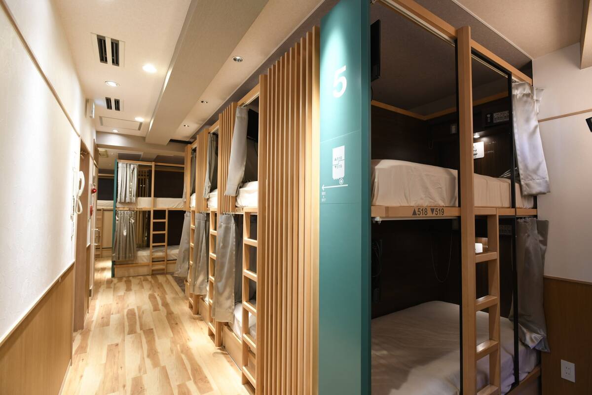 A corridor with bunk beds, wooden partitions, and a number sign indicating room 5.