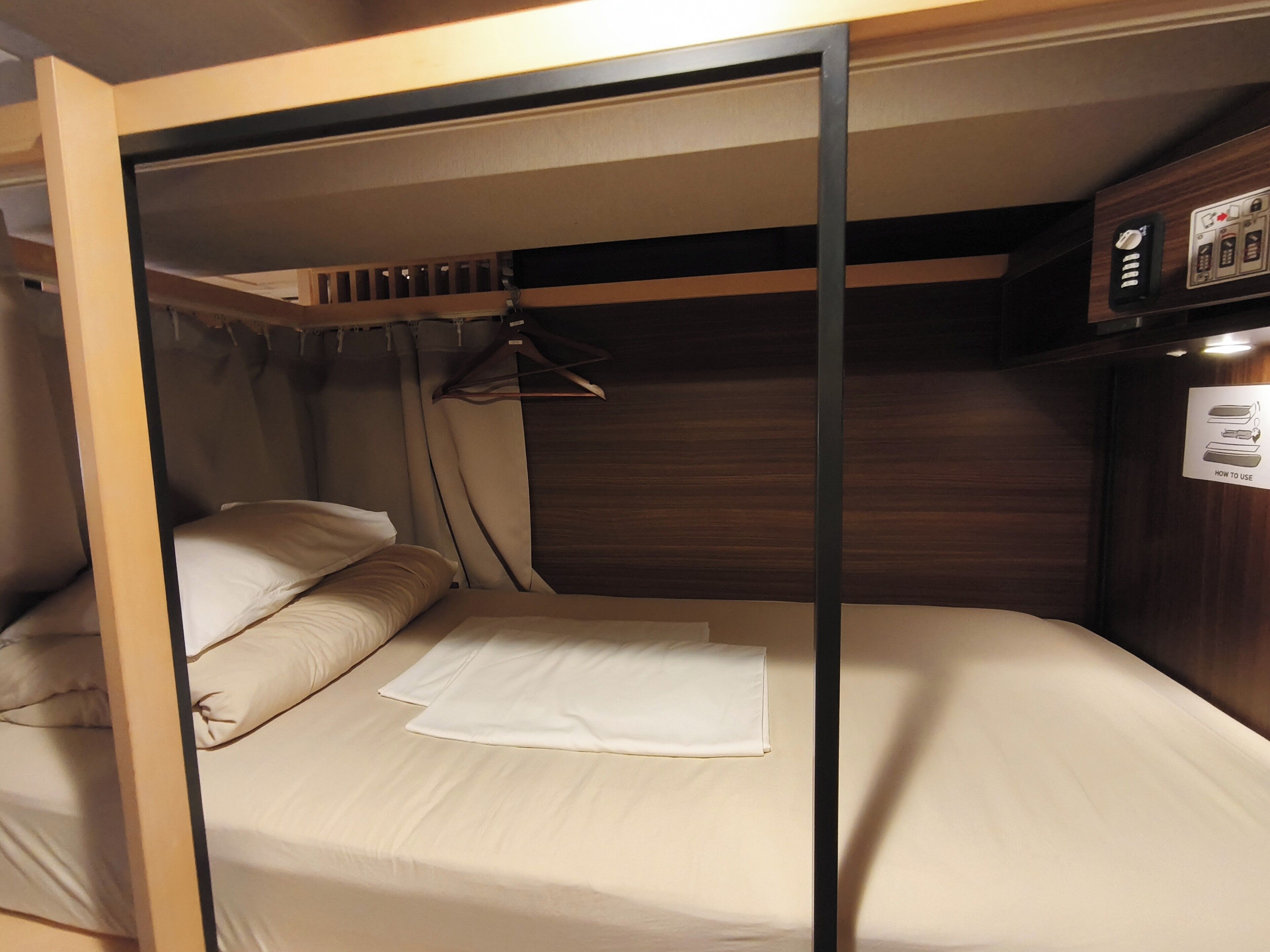 A compact bunk bed with a hanging light fixture and a control panel on the wall.