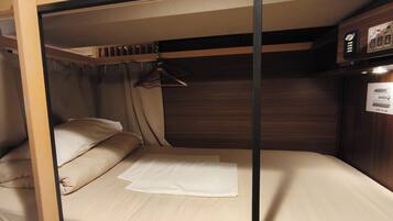 A compact bunk bed with a hanging light fixture and a control panel on the wall.
