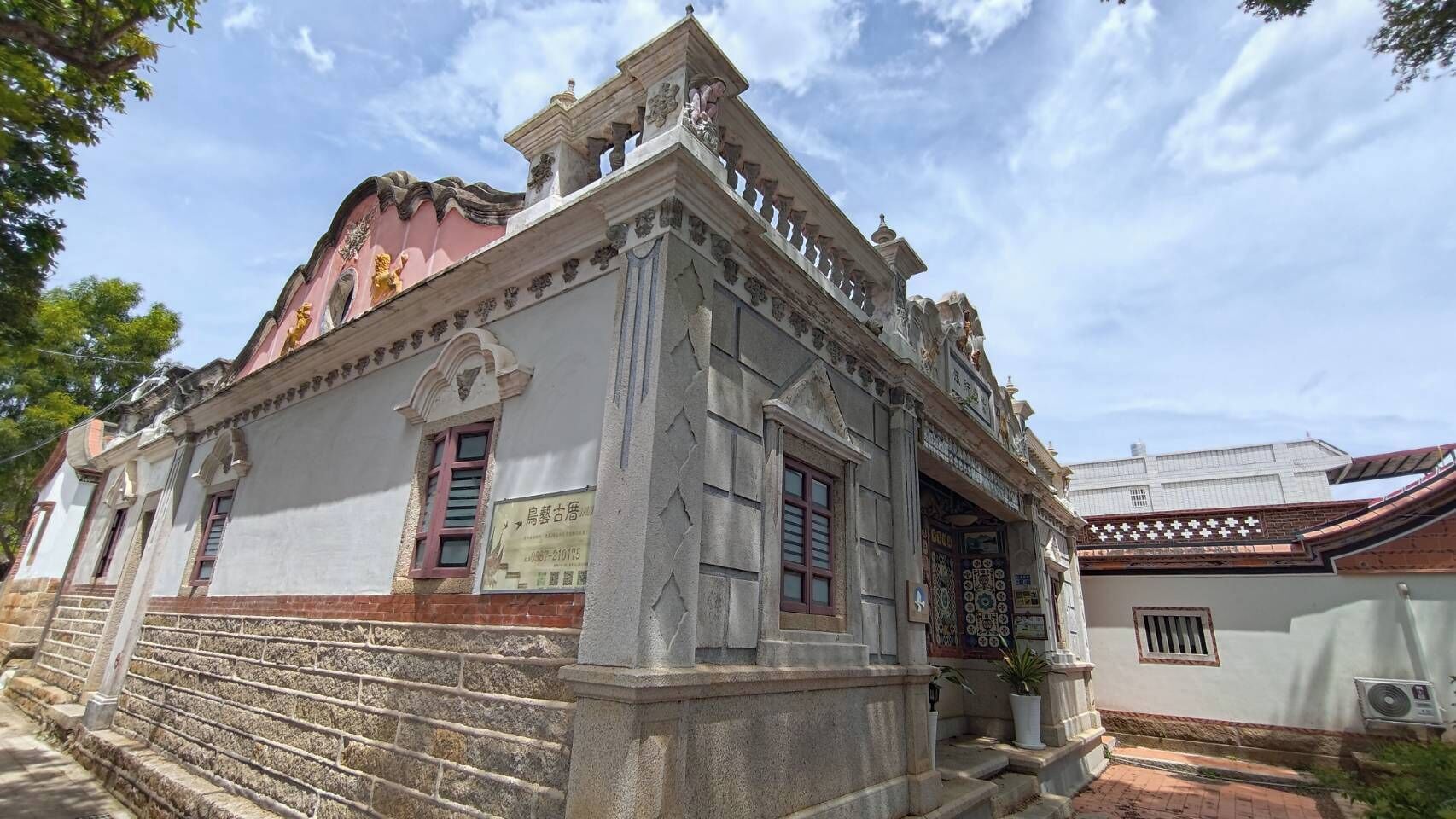 Un edificio histórico con fachada de piedra, un balcón y una entrada tradicional con tejas.