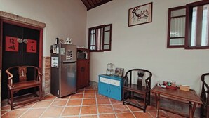 Eine kleine Küche mit Kühlschrank, Mikrowelle und einem blauen Schrank. Zwei Holzsessel und ein kleiner Tisch sind ebenfalls vorhanden.