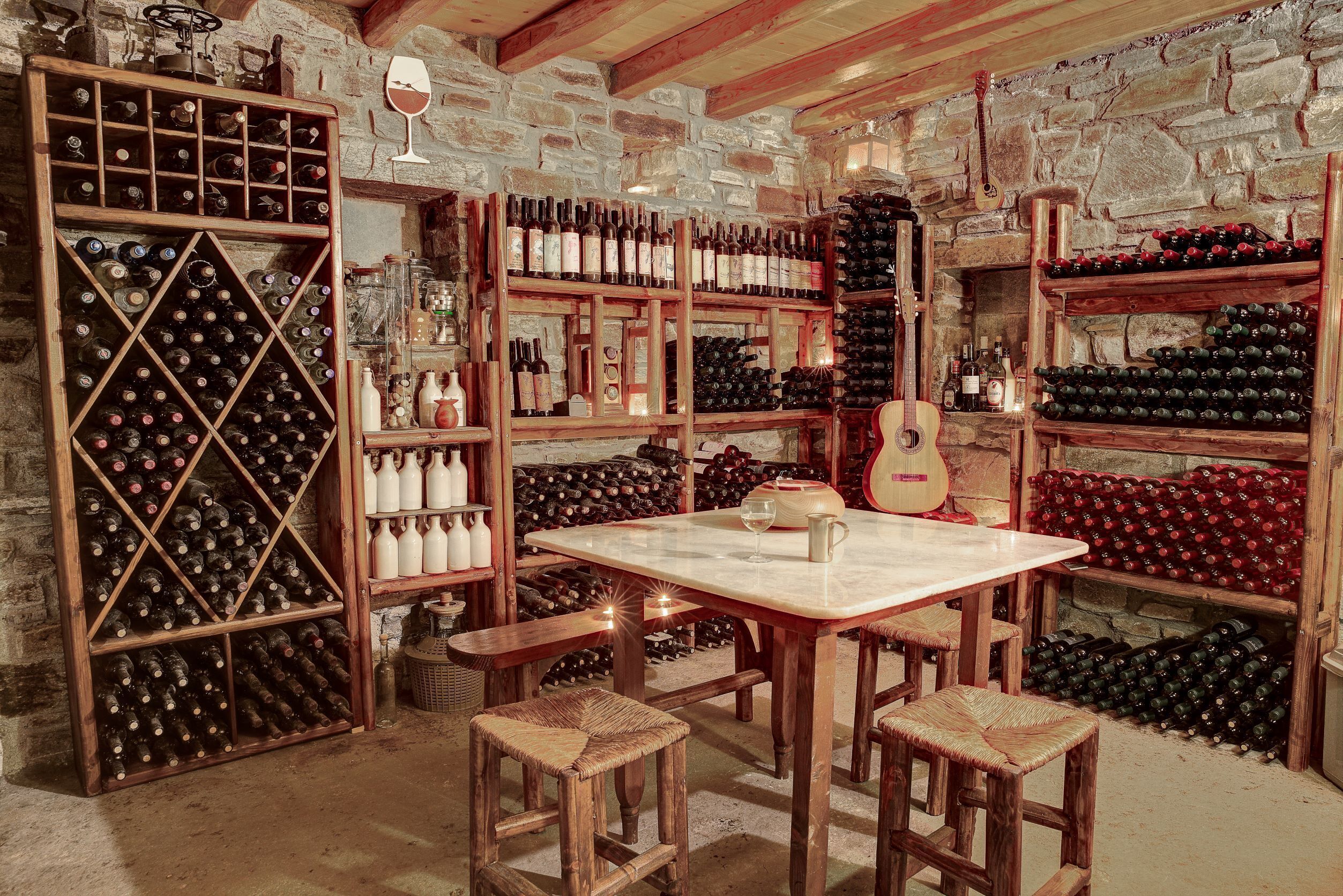 A wine cellar with wooden shelves and tables, bottles of wine, and a guitar.