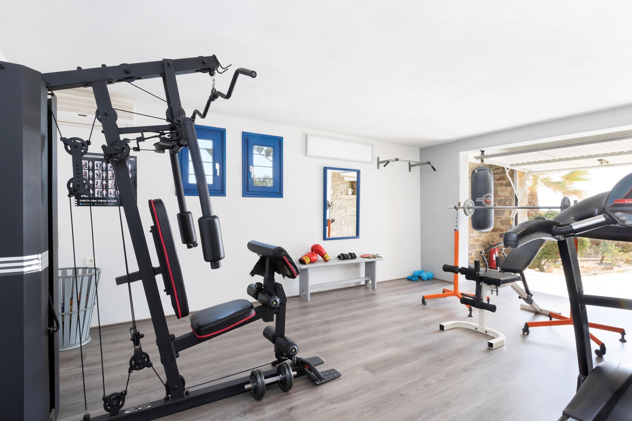 Una palestra domestica con panca per pesi, rack per squat e tapis roulant.