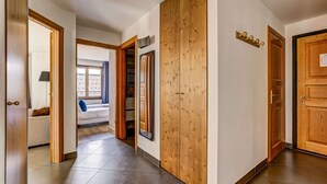 A hallway with wooden doors, a tiled floor, and a window with curtains.
