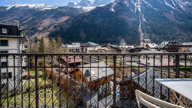 A mountain view with a balcony featuring wrought iron railings.