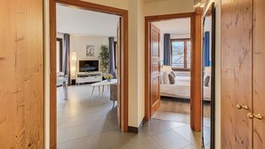 A hallway leading to a living area with a TV, a dining table, and a bed.