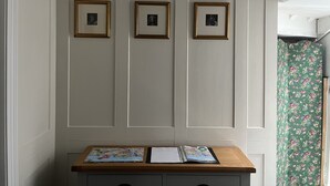 Una habitación con un escritorio de madera, tres cuadros enmarcados en la pared y una cortina floral verde.